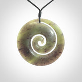 This picture shows a large hand carved jade koru pendant. It is a darker green colour which is quite translucent where the jade is thin. Although a large piece, it is a wonderful, delicate piece of jewellery. The cord is hand plaited and adjustable so that you can position the pendant where it suits you best.